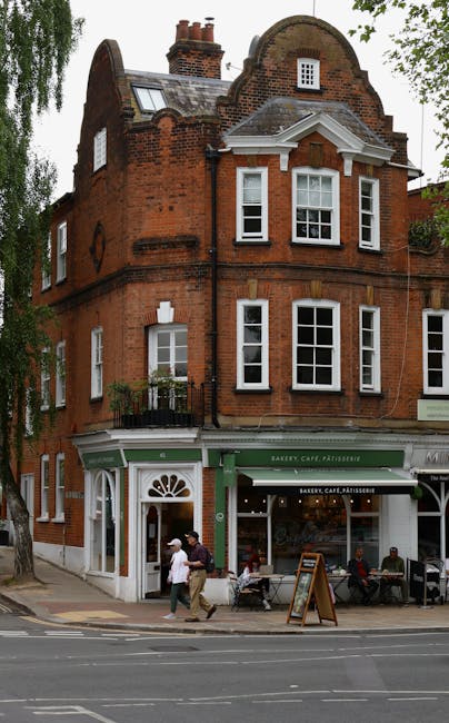 A row of historic residential buildings with Victorian-style architecture, featuring large sash windows and ornate cornices, painted in pastel shades of cream, dark blue, bright green, and pink. The b